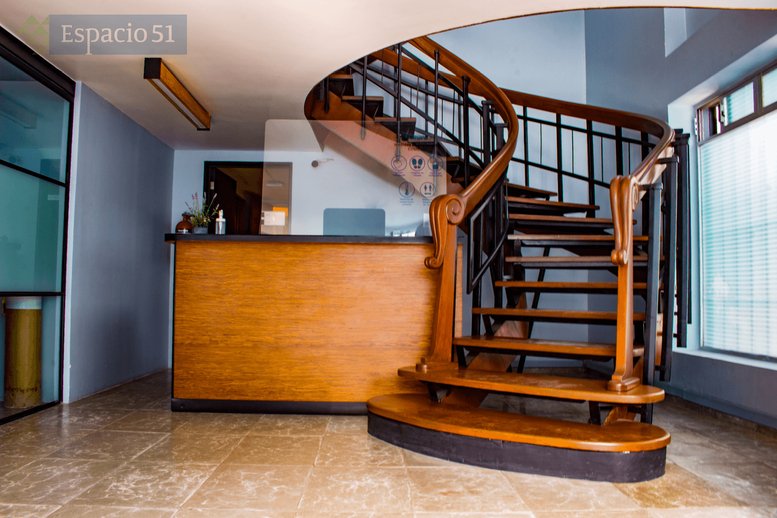 Reception area at Av Tres num 51, Col. San Pedro de los Pinos with a wooden desk and elegant spiral staircase.