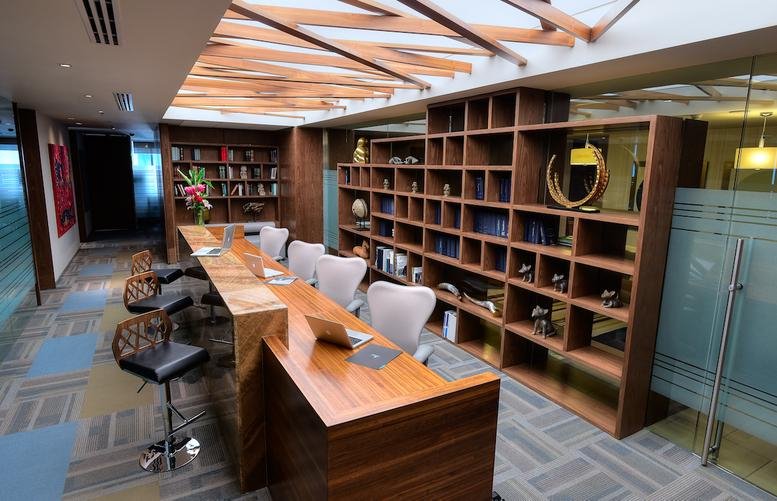 Reception area at Av. Batallón de San Patricio #111 with wooden desk and expansive shelving.