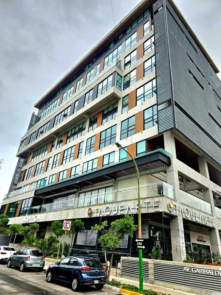 Exterior view of the contemporary multi-story glass and stone building at Av. Rubén Darío 425.