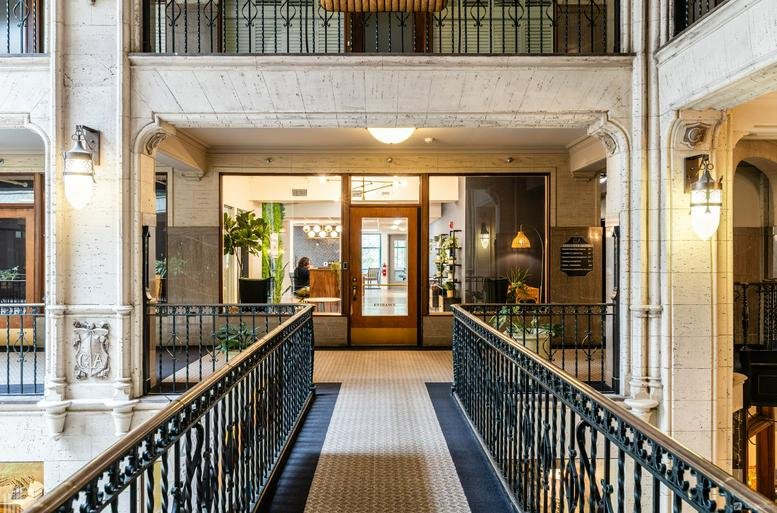 Grand indoor walkway with stone arches and ornate railings at 1 Page Avenue.