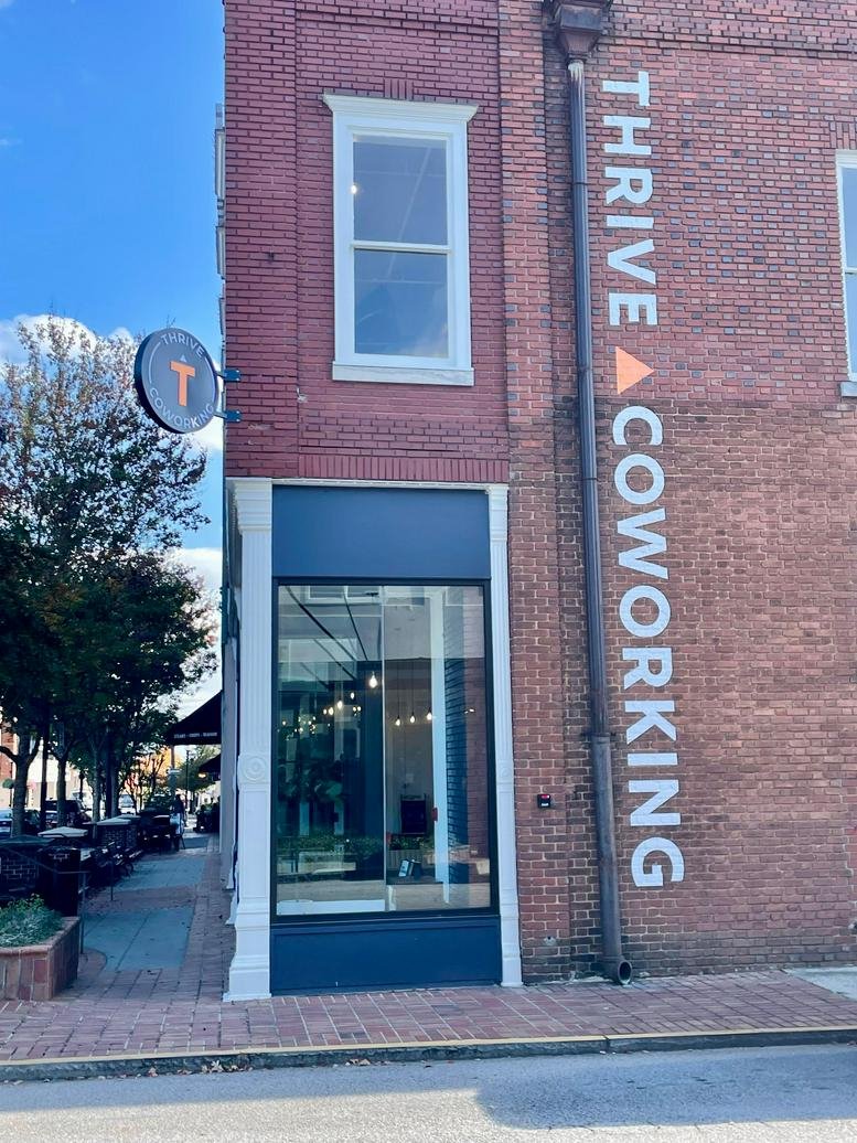 Exterior brick facade of Thrive Coworking with large windows and vertical signage.