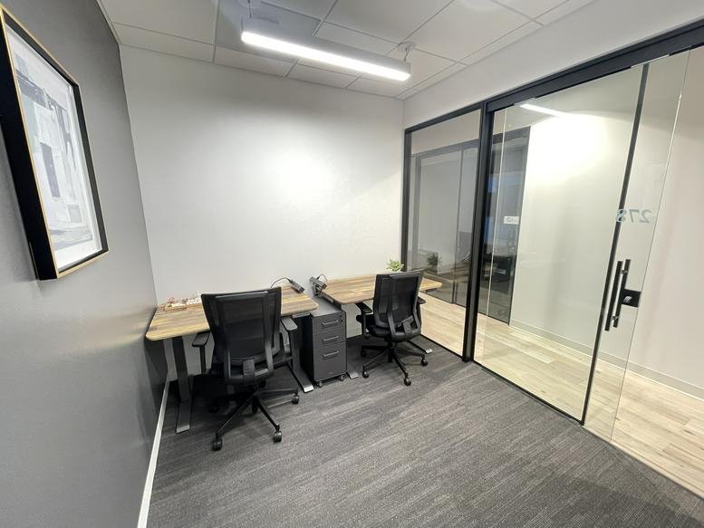 Two-person private office with wooden desks and grey carpet.