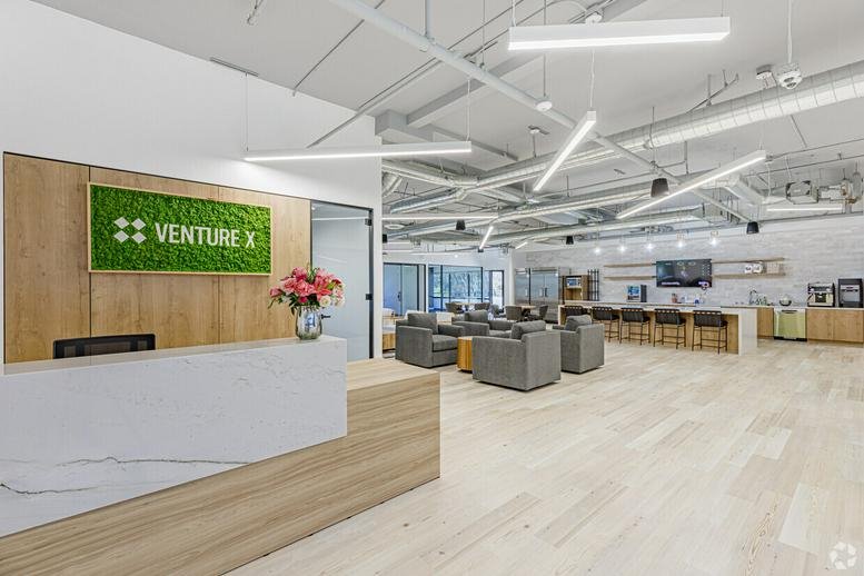 Bright reception area for Venture X at 10089 Willow Creek Road featuring a moss wall and marble desk.