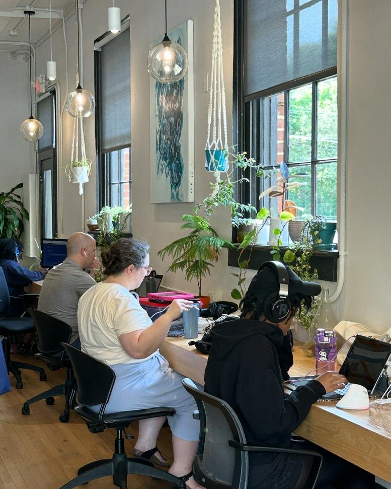 Coworking space at 102 Hillsboro Street with hanging plants and pendant lighting.