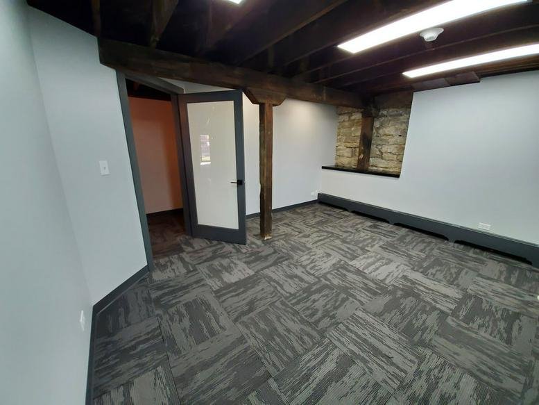 Spacious office suite featuring exposed wood beams and a stone accent wall.