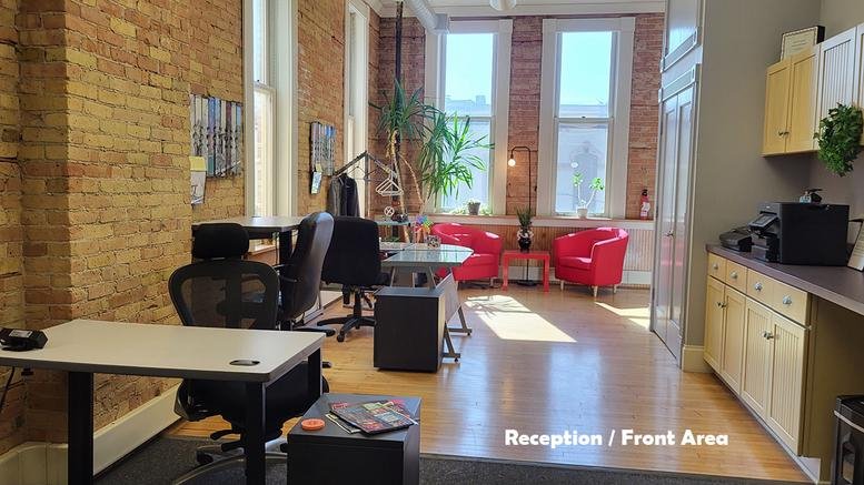 Bright reception area at 11 Douglas Avenue, Second Floor, Elgin with exposed brick walls and red accent chairs.
