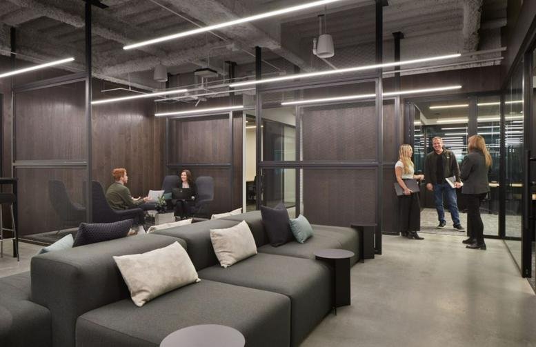 Modern lounge with dark grey modular sofas and wooden panelled walls at 1100 Dexter Ave N.