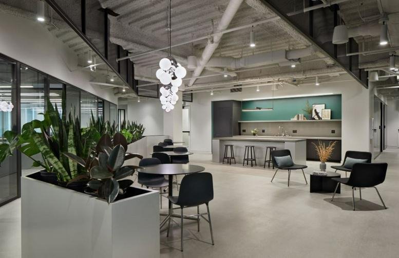 Bright open cafe and breakout area featuring a marble island, teal accents, and modern lighting.