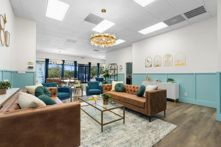 Expansive interior view showing multiple lounge areas, warm wood floors, and bright overhead lighting.