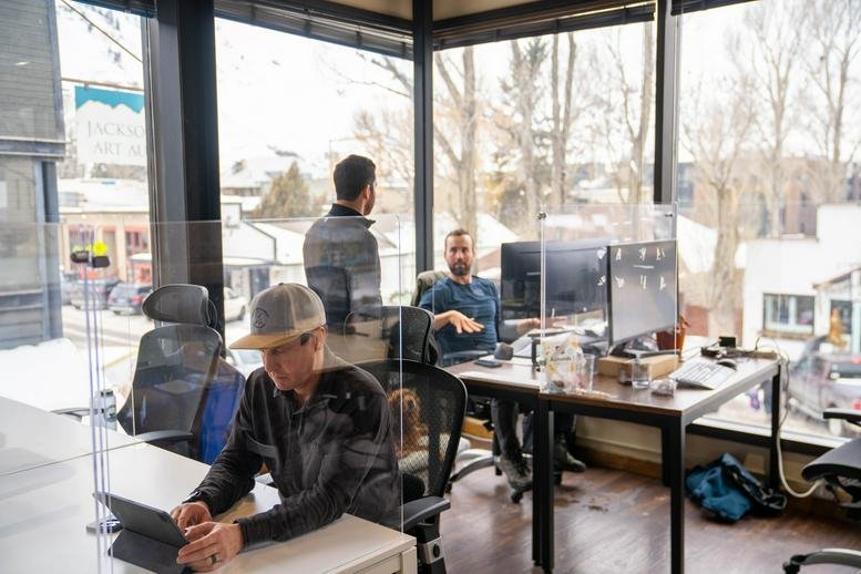 Open-plan coworking space at 140 East Broadway Avenue, Suite 25, with large windows and glass partitions.