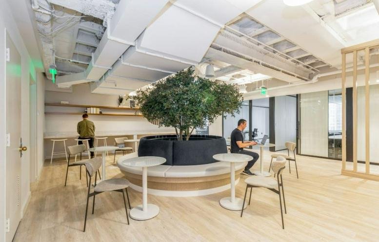 Bright communal lounge at 1700 Market Street, Philadelphia, Pennsylvania featuring a central tree and circular seating.