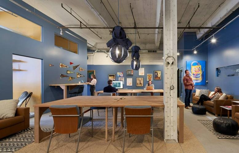 Spacious communal coworking area at 1821 West Hubbard Street, Suite 209, featuring high ceilings and blue walls.