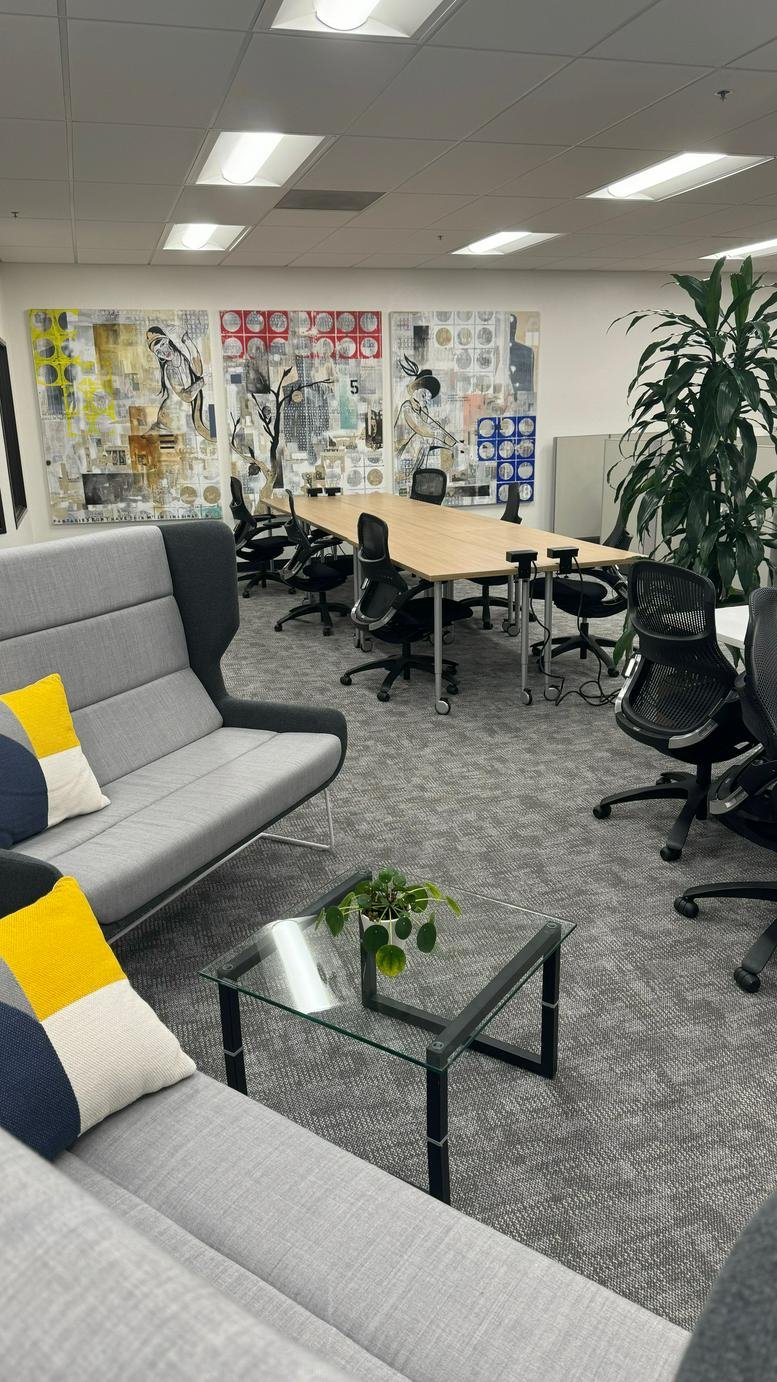 Spacious lounge area with gray sofas, colorful pillows, and large colorful art pieces on the wall.