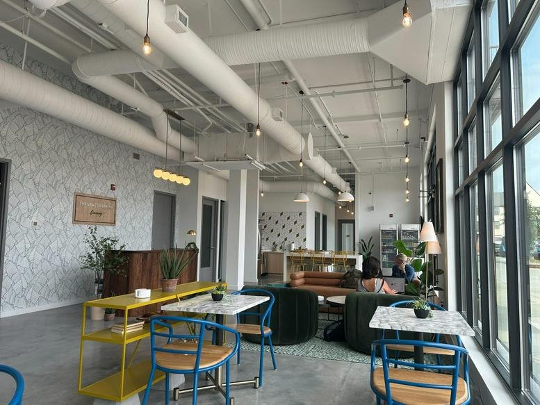 Spacious sunlit common area at 2100 Westshore Drive, Cumming, Georgia with cafe seating and industrial ceilings.