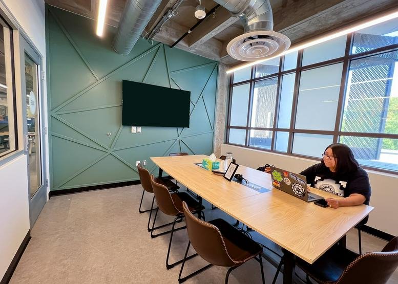Meeting room at 225 East Main Street, Suite 201 featuring a geometric teal accent wall and long wooden table.