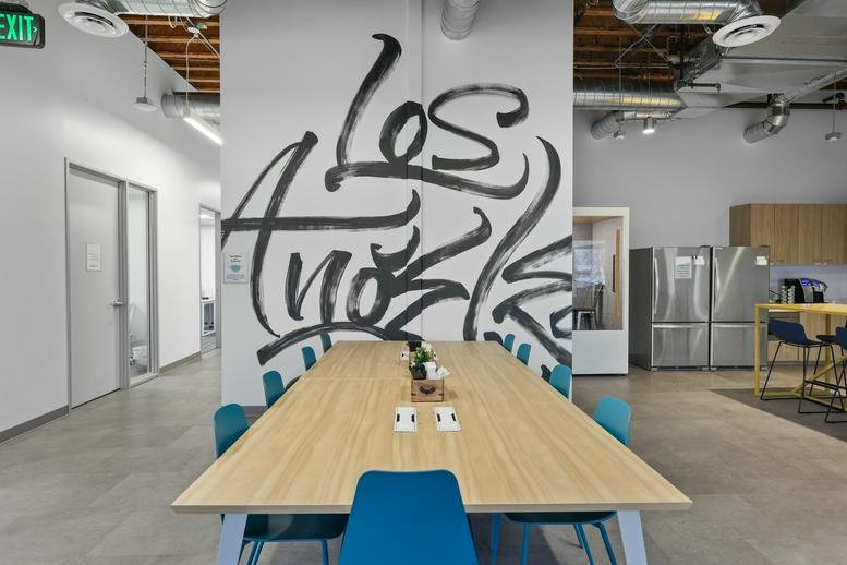 Bright coworking space at 2335 West 208th Street featuring a large Los Angeles mural and wooden table.