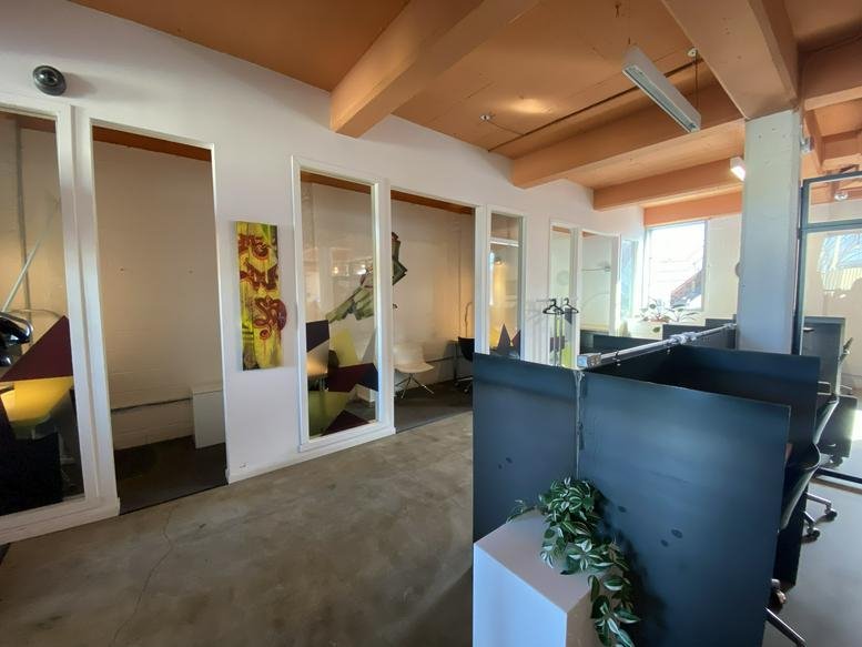 Wide view of a modern industrial office at 2700 Rue Angus featuring exposed wood beams and glass partitions.