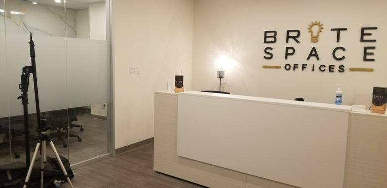 Bright reception area with white desk and branded signage at 30 Eglinton Ave West.