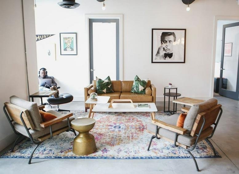 Spacious sunlit lounge with leather furniture, a patterned rug, and wall art.