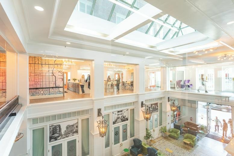 Grand multi-level atrium with a large skylight and historic architectural details.