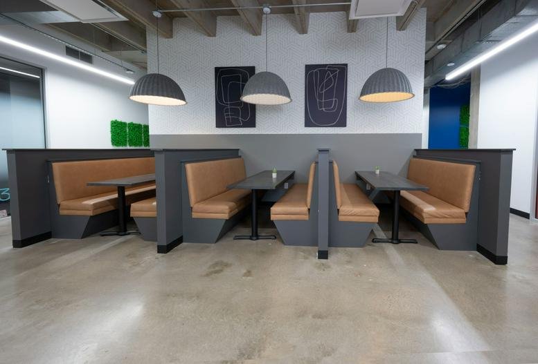 Modern dining area at 5757 Woodway Drive, Suite 300, featuring tan leather booths and grey dome pendant lights.