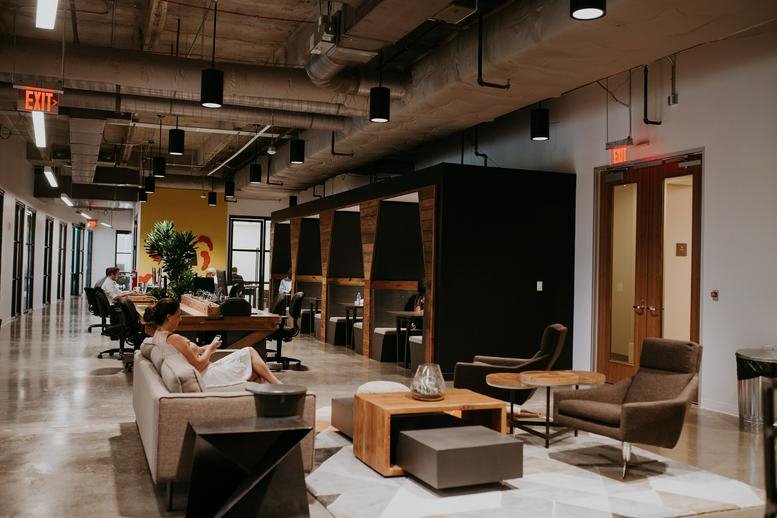 Spacious lounge area featuring leather armchairs and exposed concrete ceilings.