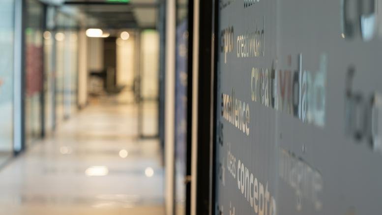 Close-up of frosted glass wall with text detail leading into a bright office corridor.