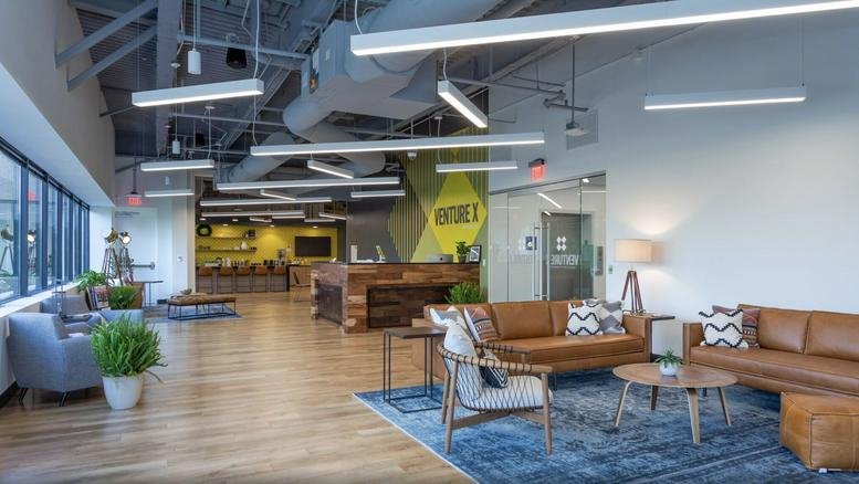 Spacious communal lounge at Frontier 600 with leather sofas, blue rug, and industrial ceilings.