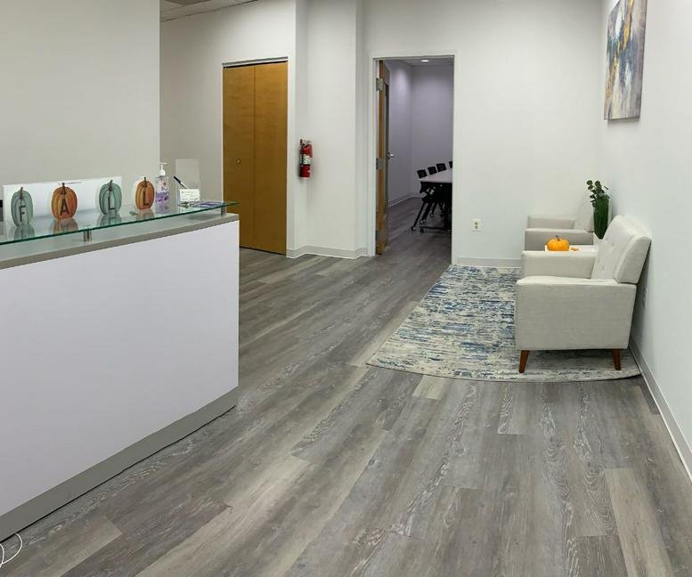 Bright reception area at 7004 Security Boulevard, Suite 300 with a white front desk and comfortable seating.