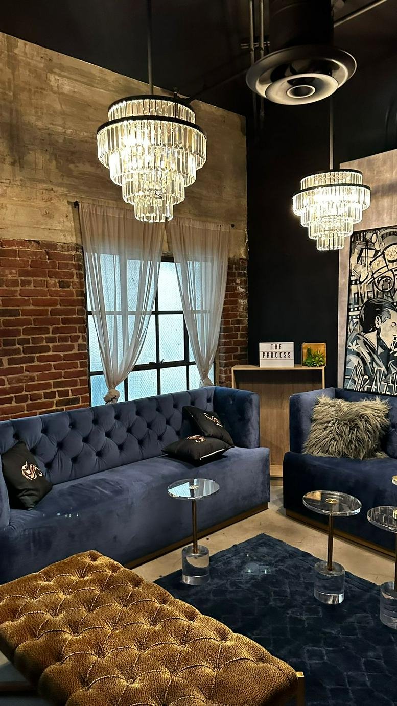 Lounge area at 7046 Hollywood Boulevard with velvet sofas, crystal chandeliers, and exposed brick.