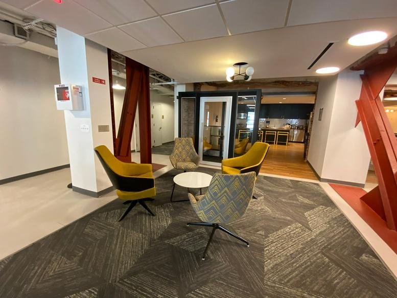 Bright common area at 740 15th Street North West with yellow accent chairs and a small meeting booth.