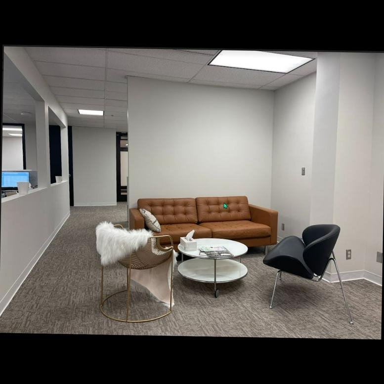 Warm modern lounge at 8700 Indian Creek Parkway featuring a tan leather sofa and white shag chair.