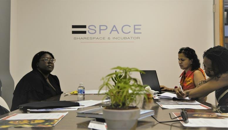 A professional meeting room at 89, Market Street, Newark featuring people around a wooden conference table.