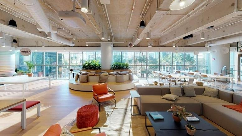 Spacious communal lounge at Avenida Faria Lima 4055 with colorful seating, plants, and high industrial ceilings.