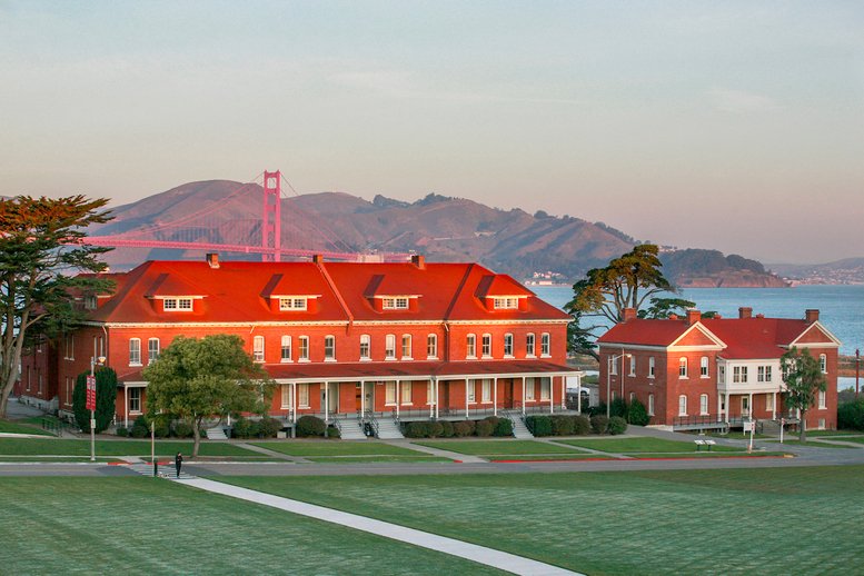 Exterior view of the historic red brick 103 Montgomery St with the Golden Gate Bridge in the background.
