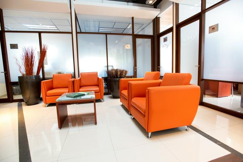 Reception area with bright orange armchairs and a small coffee table.
