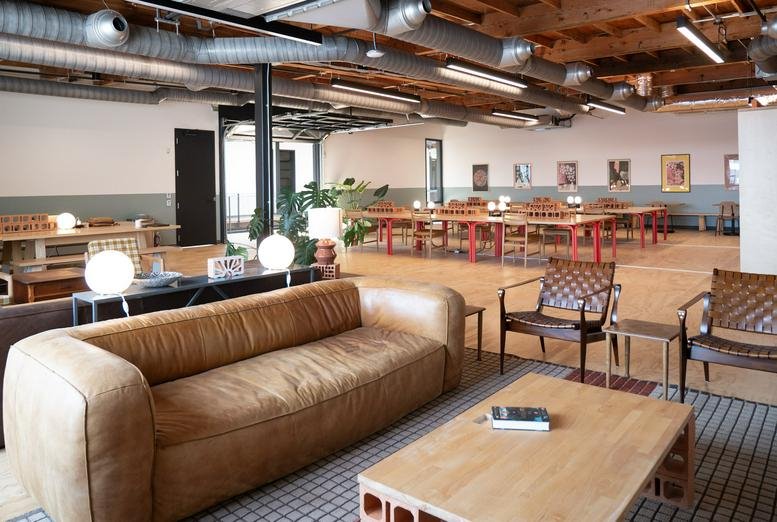 Spacious communal lounge at The Pioneer Collective, West Canal Yards, Seattle with leather sofa and industrial ceiling.