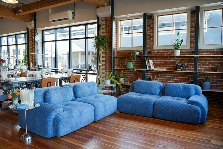 Spacious communal lounge at Kinship with plush blue modular sofas and large windows.