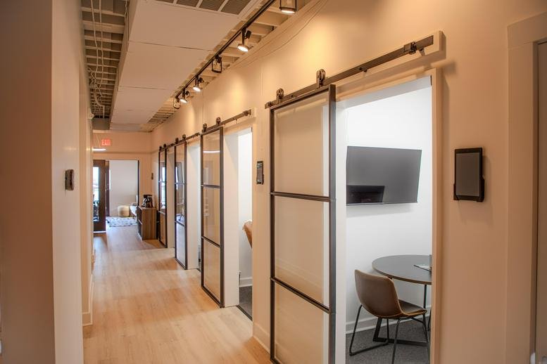 Long view down a hallway with glass-paned sliding doors leading to private suites.