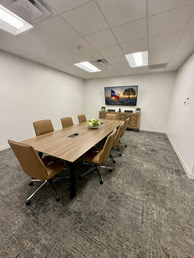 Modern conference room at 122 West Building featuring a long wooden table and Texas-themed art.