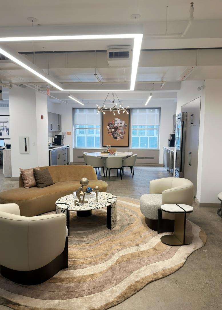 Spacious communal lounge at 125 Maiden Lane with a large curved rug, leather sofa, and modern armchairs.