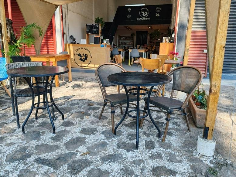 Exterior entrance area of Conejo Negro Coworking with stone flooring and outdoor seating.