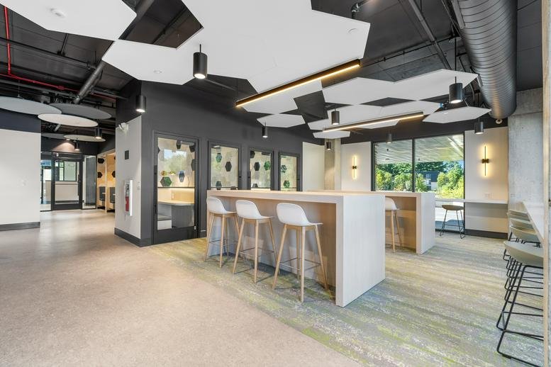 Spacious communal lounge with modern hexagonal ceiling panels and high-top tables.
