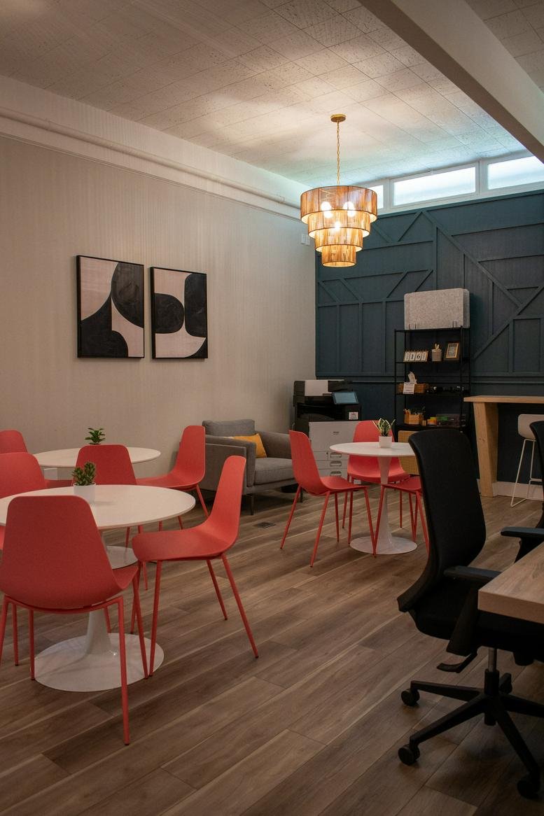 Bright communal lounge at Work Space featuring red chairs and modern chandelier.