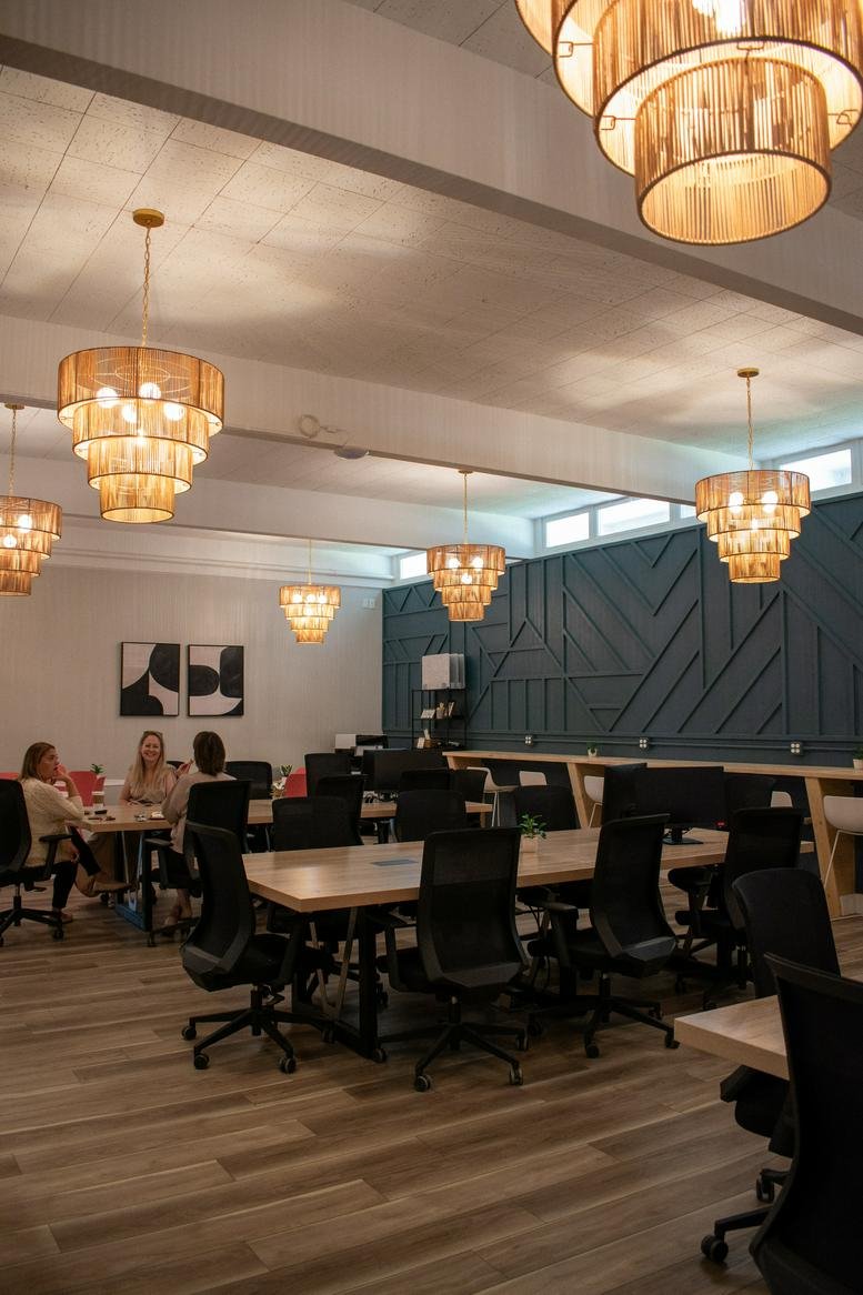 Open coworking space at Work Space, 1521 East Perkins Avenue with multiple wooden tables and chandeliers.