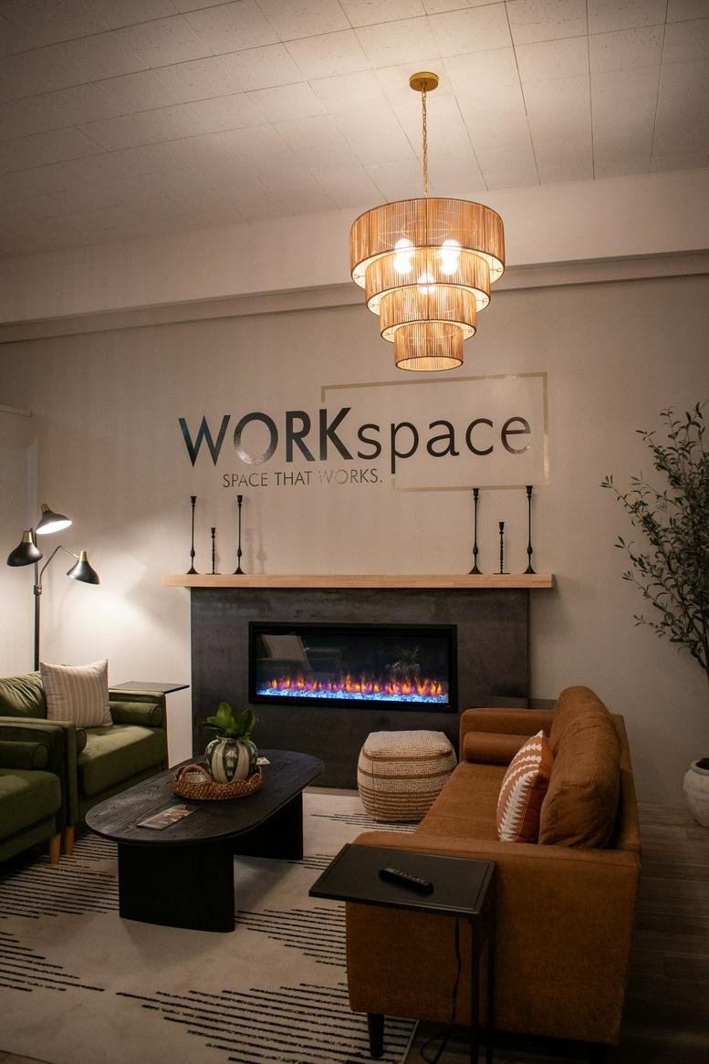 Lounge area at Work Space with a fireplace, leather sofa, and green armchairs.