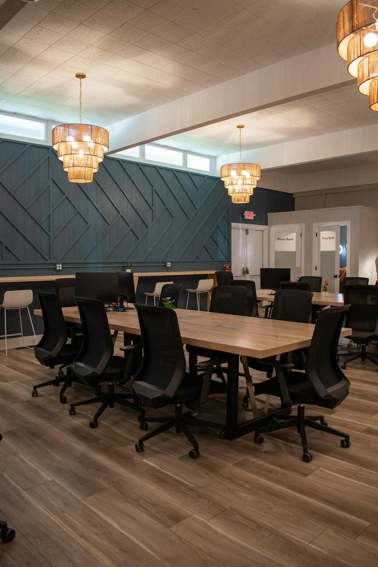 Large open-plan coworking space with multiple workstations and stylish wicker chandeliers.