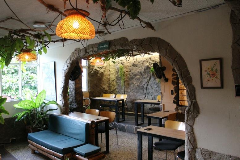 The cave-themed coworking lounge at Hotel Grand Ilama with natural rock walls and hanging vines.