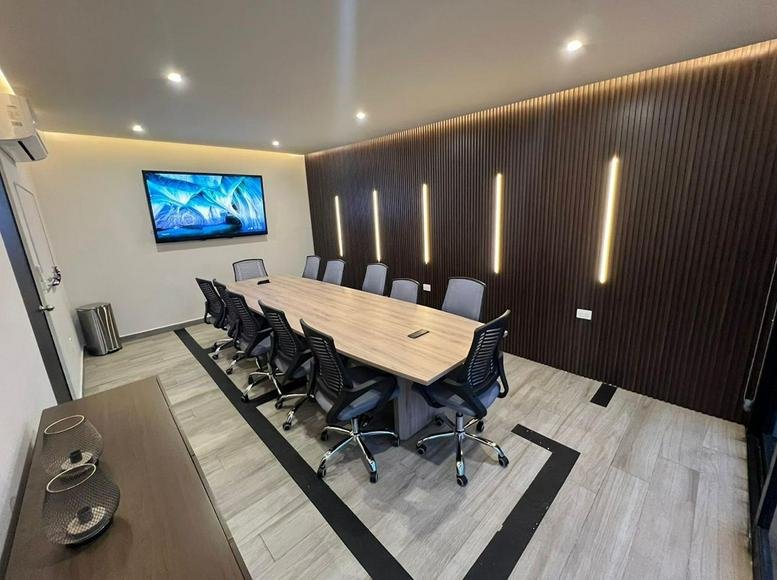 Meeting room at Ocampo Business Center with wooden feature wall and long conference table.