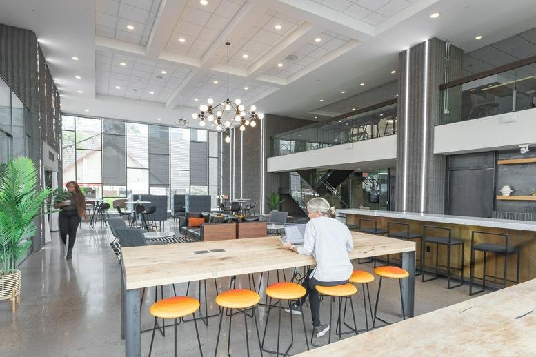 Spacious two-story lobby at 2828 North Central Avenue with a modern chandelier and wood-topped communal table.